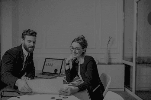 En mann og en dame som ser på regneark